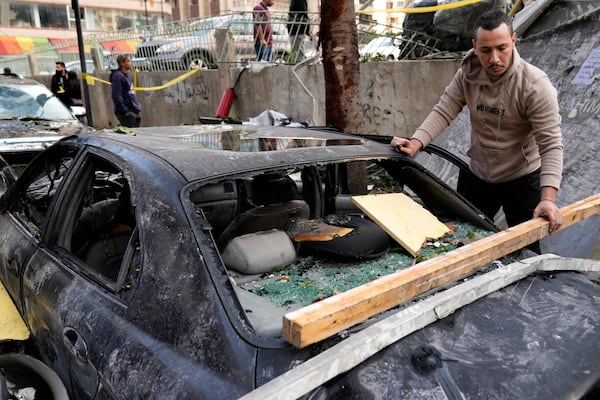 A man removes debris from his damaged car at the site where an Israeli airstrike on Sunday evening hit in central Beirut, Lebanon, Monday, Nov. 18, 2024. (AP Photo/Hussein Malla)