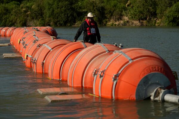 FILE - A kayaker walks past large buoys being used as a floating border barrier on the Rio Grande, Aug. 1, 2023, in Eagle Pass, Texas. (AP Photo/Eric Gay, File)