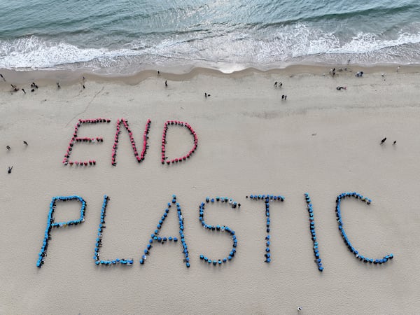 Environment activists perform a human sign calling for a strong global plastics treaty ahead of the fifth session of the Intergovernmental Negotiating Committee on Plastic Pollution which sets to be held from Nov. 25 to Dec. 1 on the beach in Busan, South Korea, Sunday, Nov. 24, 2024. (Son Hyung-joo/Yonhap via AP)