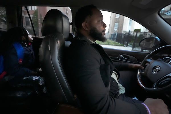 PiggyBack Network co-founder & CEO Ismael El-Amin, right, and Messiah Robinson, 6, wait outside the home of Takia Phillips, 15, on Friday, Oct. 18, 2024, as El-Amin drives the two children to school as part of the PiggyPack ride-share network in Chicago. (AP Photo/Charles Rex Arbogast)