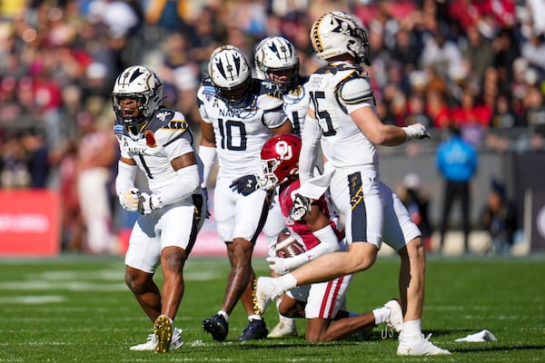 Navy cornerback Dashaun Peele (1) reacts after making a tackle against Oklahoma wide receiver Zion Ragins, bottom right, during the first half of the Armed Forces Bowl NCAA college football game, Friday, Dec. 27, 2024, in Fort Worth, Texas. (AP Photo/Julio Cortez)