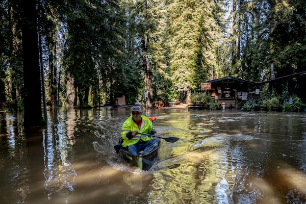 John Phillips, front, and neighbor Kevin Ozorkiewicz row a canoe at the flooded Mirabel RV Park & Campground after a major storm in Forestville, Calif., Saturday, Nov. 23, 2024. (Stephen Lam/San Francisco Chronicle via AP)