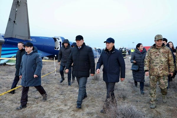 In this photo taken from a video released by the administration of Mangystau region, Members of an investigation committee and local officials walk past the wreckage of Azerbaijan Airlines' Embraer 190 lying on the ground near the airport of Aktau, Kazakhstan, on Thursday, Dec. 26, 2024. (The Administration of Mangystau Region via AP)