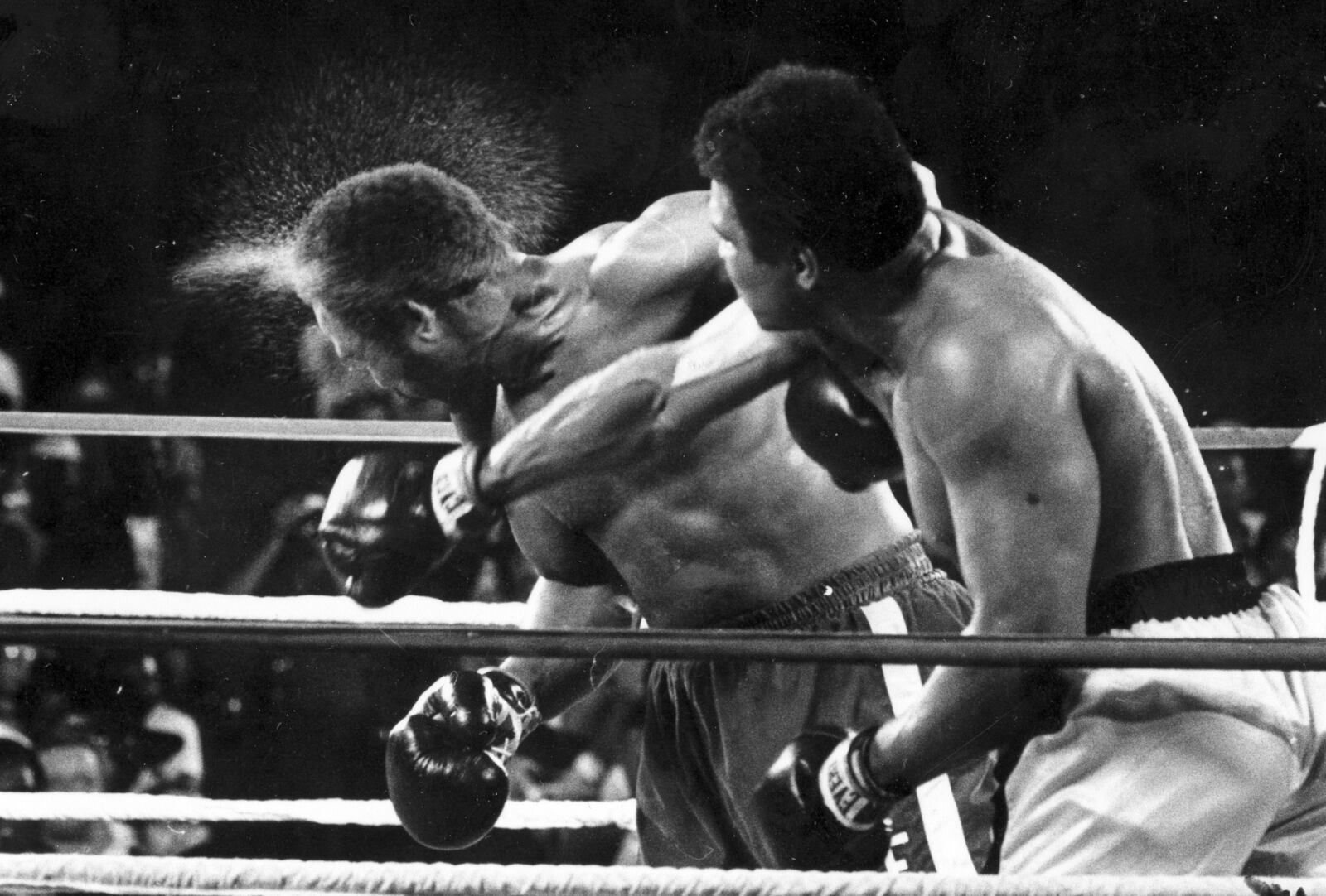 FILE - Perspiration flies from the head of George Foreman as he takes a right from challenger Muhammad Ali in the seventh round in the match dubbed Rumble in the Jungle in Kinshasa, Zaire on Oct. 30, 1974. (AP Photo/Ed Kolenovsky, File)