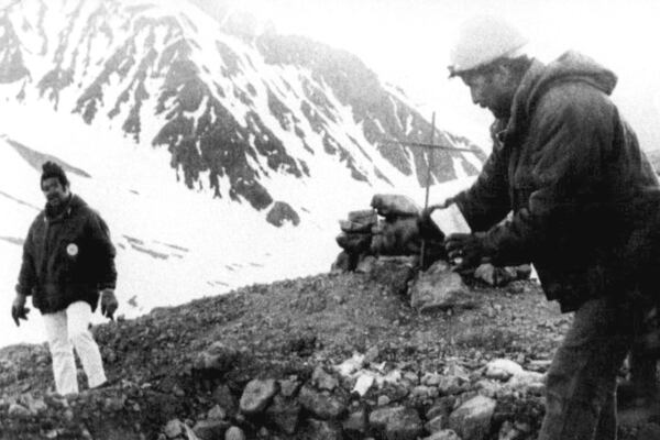 FILE- A member of the Andean Group Rescue Corp throws a handful of earth over the common grave of 29 victims of a Uruguayan plane that crashed in the Chilean Andes mountains Oct,. 13, 1972. There were 16 survivors who were rescued 70 after the crash on Dec. 23, 1972. (AP Photo/File)