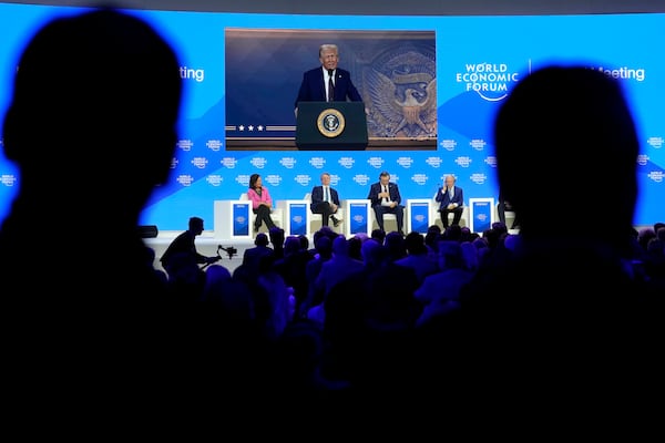 People follow a virtual speech of U.S. president Donald Trump at the Annual Meeting of World Economic Forum in Davos, Switzerland, Thursday, Jan. 23, 2025. (AP Photo/Markus Schreiber)