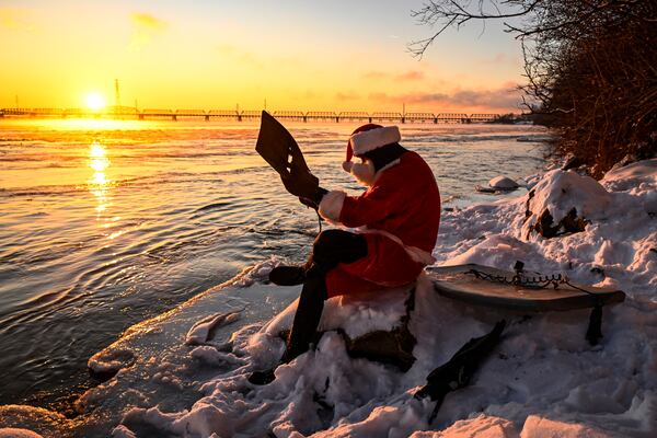 Carlos Hebert Plante, who boogie boards daily, dressed as Santa Claus gets ready to hit the St-Lawrence Riveramid an air temperature of -14 degrees Celsius on Christmas Day, in Montreal, Wednesday, Dec. 25, 2024. (Bernard Brault /The Canadian Press via AP)