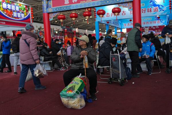 Elderly people with their purchased goods rest as people shop at a New Year bazaar set up for the upcoming Chinese Lunar New Year, in Beijing on Jan. 13, 2025. (AP Photo/Andy Wong)