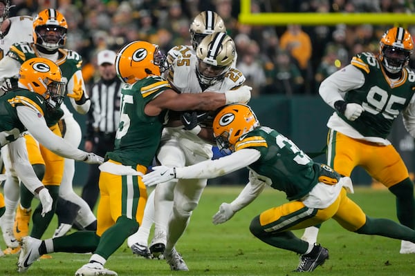 New Orleans Saints running back Kendre Miller (25) is stopped by Green Bay Packers linebacker Eric Wilson and safety Zayne Anderson, right, during the first half of an NFL football game, Monday, Dec. 23, 2024, in Green Bay, Wis. (AP Photo/Morry Gash)