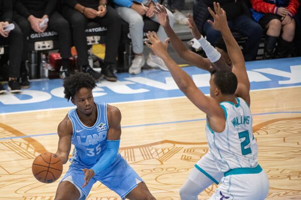 Cleveland Cavaliers' Isaac Okoro (35) passes around Charlotte Hornets' Grant Williams (2) during the first half of an NBA basketball game in Cleveland, Sunday, Nov 17, 2024. (AP Photo/Phil Long)