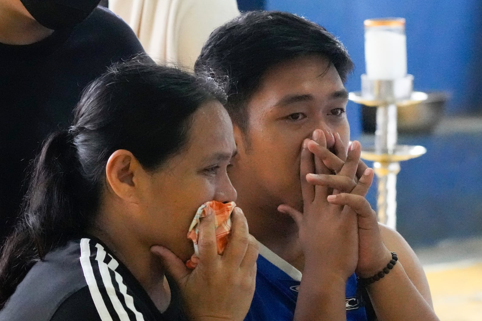 Family and their friend grieve as they watch over their loved ones at a basketball court where the coffins of landslide victims were placed after Tropical Storm Trami recently struck Talisay, Batangas province, Philippines on Saturday, Oct. 26, 2024. (AP Photo/Aaron Favila)