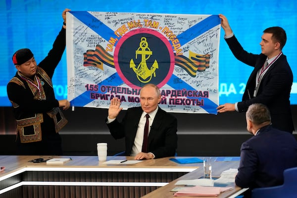 Men hold a replica of the banner of the 155th Marine Brigade of the Pacific Fleet, participating in a special military operation in Ukraine during Russian President Vladimir Putin's annual news conference and call-in show at Gostinny Dvor in Moscow, Russia, Thursday, Dec. 19, 2024. (AP Photo/Alexander Zemlianichenko)