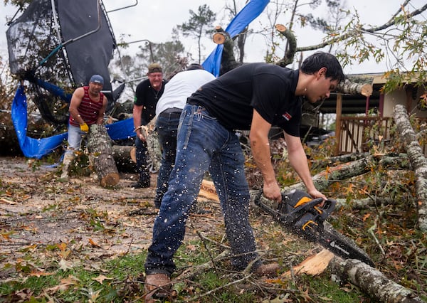 Ricardo Rodriguez uses a chain saw to remove debris from a woman's home after strong thunderstorms pass through the Greater Houston region, Saturday, Dec. 28, 2024, in Porter Heights. (Jason Fochtman/Houston Chronicle via AP)