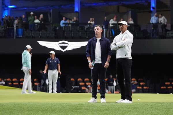 Tiger Woods, right, and Rory McIlroy and stand on the green as they watch New York Golf Club and The Bay Golf Club warmup for the inaugural match of the TMRW Golf League, Tuesday, Jan. 7, 2025, in Palm Beach Gardens, Fla. TGL features six teams of four players competing against each other in a tech-infused arena the size of a football field. (AP Photo/Rebecca Blackwell)