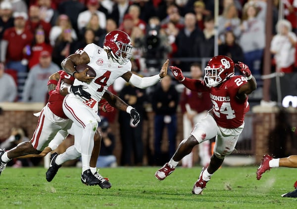 Alabama quarterback Jalen Milroe (4) runs the ball in front of Oklahoma linebacker Samuel Omosigho (24) during the first quarter of a NCAA college football game Saturday, Nov. 23, 2024, in Norman, Okla. (AP Photo/Alonzo Adams)