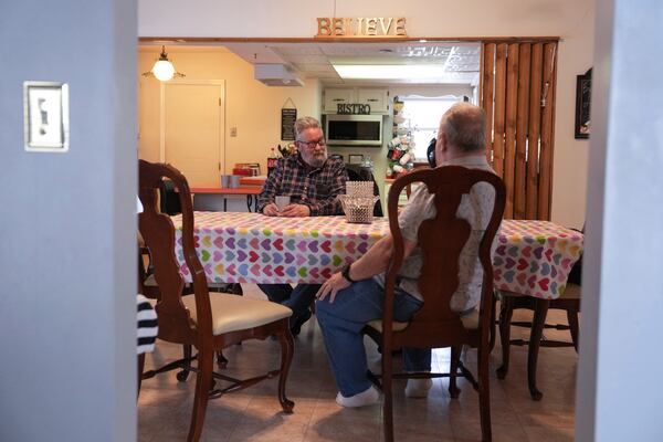 Bill Teager, left, Dora Bronston, background, and Paul Gomia, right, talk politics at Bronston's home, Tuesday, Jan. 14, 2025, in Middletown, Ohio. The city is the hometown of Vice President-elect JD Vance.(AP Photo/Kareem Elgazzar)