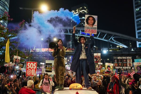 Demonstrators hold signs and flares during a protest calling for the immediate release of the hostages held in the Gaza Strip by the Hamas militant group in Tel Aviv, Israel, on Monday, Jan. 13, 2025. (AP Photo/Ohad Zwigenberg)