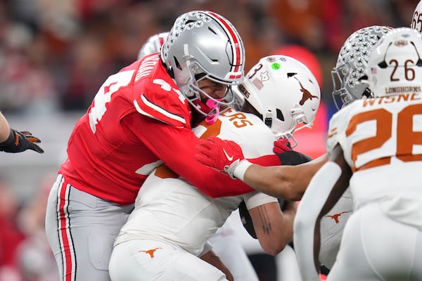 Ohio State defensive end JT Tuimoloau, left, sacks Texas quarterback Quinn Ewers during the first half of the Cotton Bowl College Football Playoff semifinal game, Friday, Jan. 10, 2025, in Arlington, Texas. (AP Photo/Julio Cortez)