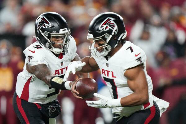 Atlanta Falcons quarterback Michael Penix Jr. (9) hands off to running back Bijan Robinson (7) during the first half of an NFL football game against the Washington Commanders, Sunday, Dec. 29, 2024, in Landover. (AP Photo/Stephanie Scarbrough)