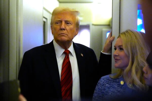 President Donald Trump speaks to reporters aboard Air Force One en route from Miami to Joint Base Andrews, Md., Monday, Jan. 27, 2025, as White House press secretary Karoline Leavitt listens. (AP Photo/Mark Schiefelbein)