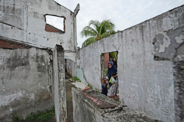 A woman walks trough an opening on the wall of a building badly damaged during the Indian Ocean tsunami in 2004 in Banda Aceh, Aceh province, Indonesia, Saturday, Dec 14, 2024. (AP Photo/Achmad Ibrahim)