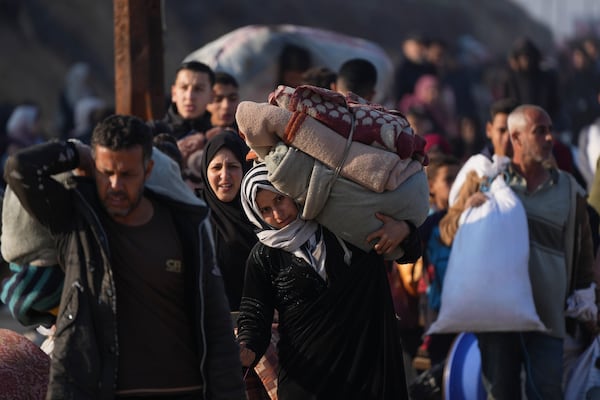 A Palestinian woman carries her belongings as she walks on a road to return to her home in the northern Gaza Strip, Tuesday, Jan. 28, 2025, after Israel's decision to allow thousands of them to go back for the first time since the early weeks of the 15-month war with Hamas. (AP Photo/Abdel Kareem Hana)