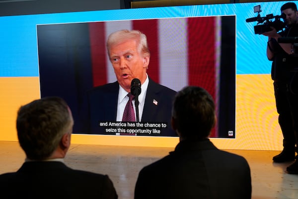 People watch the inauguration of Donald Trump on screens at the Ukraine house alongside the World Economic Forum in Davos, Switzerland, Monday, Jan. 20, 2025. (AP Photo/Markus Schreiber)