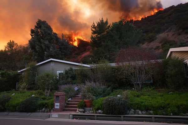 The Palisades Fire burns above a home in Mandeville Canyon, Saturday, Jan. 11, 2025, in Los Angeles. (AP Photo/Eric Thayer)