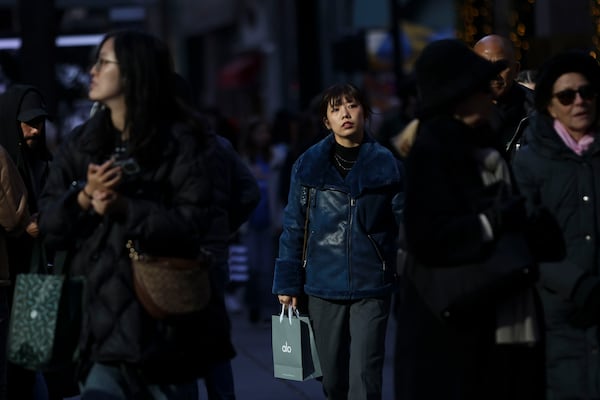 People carry shopping bags as they walk along Fifth Avenue, Friday, Nov. 29, 2024, in New York. (AP Photo/Heather Khalifa)