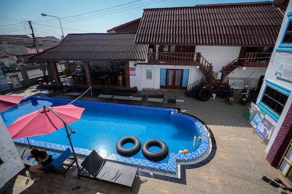 A foreign tourist rests near a swimming pool at Nana Backpackers hostel in Vang Vieng, Laos, Friday, Nov. 22, 2024. (AP Photo/Anupam Nath)