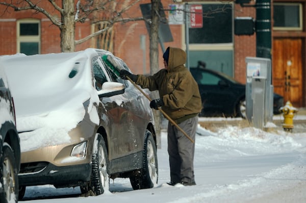 A motorist clears snow from a utility vehicle after a winter storm plunged daytime high temperatures into the single digits and left up to six inches of snow in its wake Monday, Jan. 20, 2025, in Denver. (AP Photo/David Zalubowski)