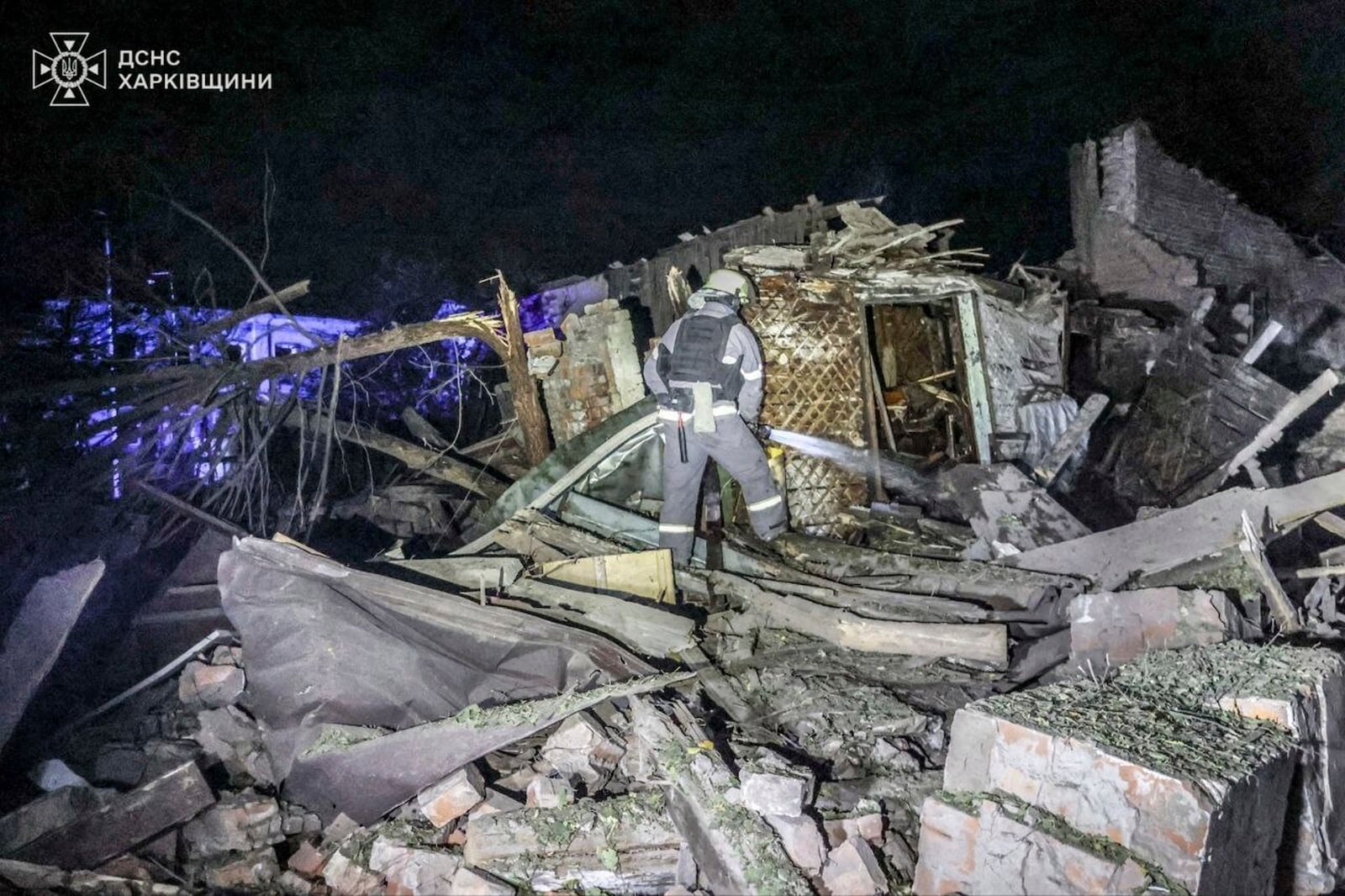 In this photo provided by the Ukrainian Emergency Service on Oct. 21, 2024, a rescue worker extinguishes a fire at a house destroyed by a Russian strike in Kharkiv, Ukraine. (Ukrainian Emergency Service via AP)