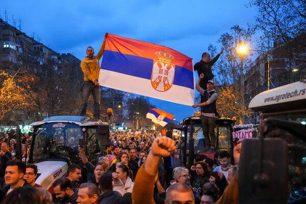 People hold a Serbian flag during a protest, day after the assault on students was carried out by thugs with baseball bats, in Novi Sad, Serbia, Tuesday, Jan. 28, 2025. (AP Photo/Darko Vojinovic)