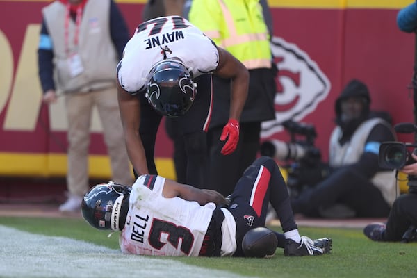 Houston Texans wide receiver Tank Dell, grabs his knee while being checked on by teammate Jared Wayne after catching a touchdown pass during the second half of an NFL football game Saturday, Dec. 21, 2024, in Kansas City, Mo. (AP Photo/Charlie Riedel)