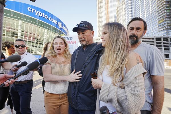 Ryan Kobayashi, center, is surrounded by friends and family while talking about his missing daughter Hannah Kobayashi outside Crypto.com Arena, Thursday, Nov. 21, 2024 in Los Angeles. (AP Photo/Damian Dovarganes)