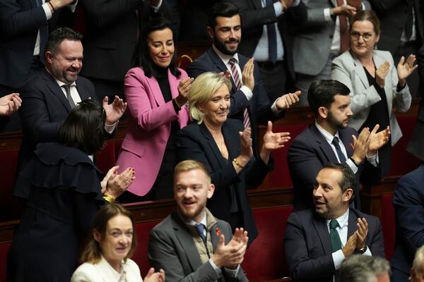 French far-right leader Marine Le Pen, center, applauds with other National Rally parliament members during conservative lawmaker Eric Ciotti's speech prior to a vote on a no-confidence motion that could bring him down and his cabinet for the first time since 1962, Wednesday, Dec. 4, 2024 the National Assembly in Paris. (AP Photo/Michel Euler)