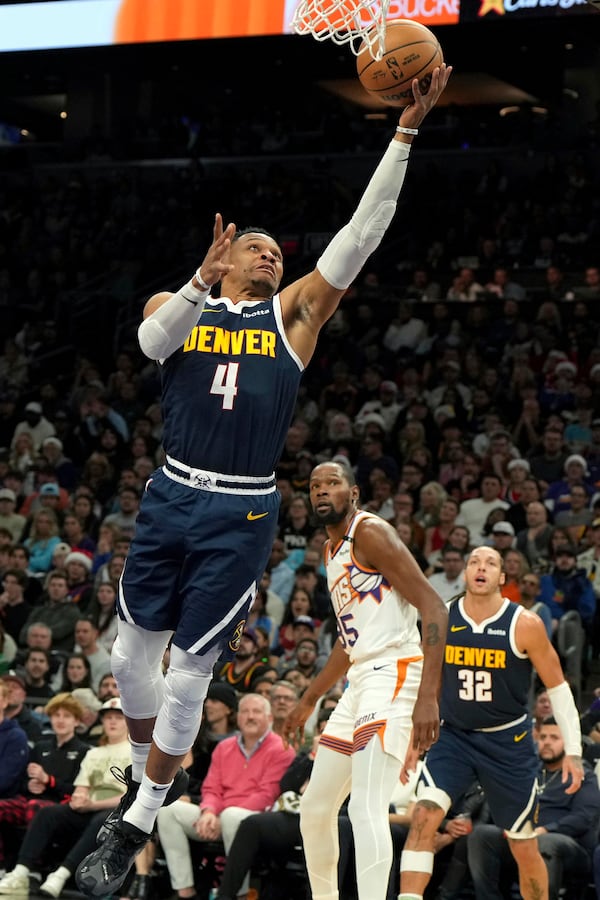 Denver Nuggets guard Russell Westbrook (4) drives past Phoenix Suns forward Kevin Durant during the first half of an NBA basketball game, Wednesday, Dec. 25, 2024, in Phoenix. (AP Photo/Rick Scuteri)