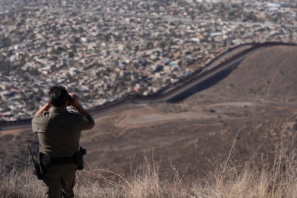 Border Patrol Agent Gutierrez looks through binoculars towards two border walls separating Mexico from the United States, Thursday, Jan. 23, 2025, in San Diego. (AP Photo/Gregory Bull)