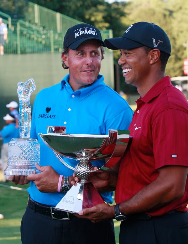 FILE - Phil Mickelson, left, and Tiger Woods pose with their trophies after the final round of The Tour Championship golf tournament at East Lake Golf Club in Atlanta Sunday, Sept. 27, 2009. Mickelson won The Tour Championship and Tiger Woods won the FedEx Cup. (AP Photo/Dave Martin)