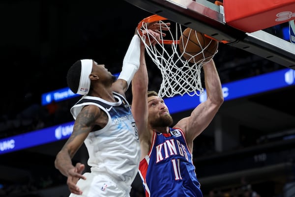 Sacramento Kings forward Domantas Sabonis (11) dunks while Minnesota Timberwolves forward Jaden McDaniels (3) defends during the first half of an NBA basketball game, Wednesday, Nov. 27, 2024, in Minneapolis. (AP Photo/Ellen Schmidt)