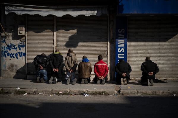 Detained men kneel down on the sidewalk as members of the new security forces take part in an operation to detain suspected people of being part of militias or loyalist soldiers of the ousted president Bashar Assad in Homs, Syria, Friday, Jan. 3, 2025. (AP Photo/Leo Correa)