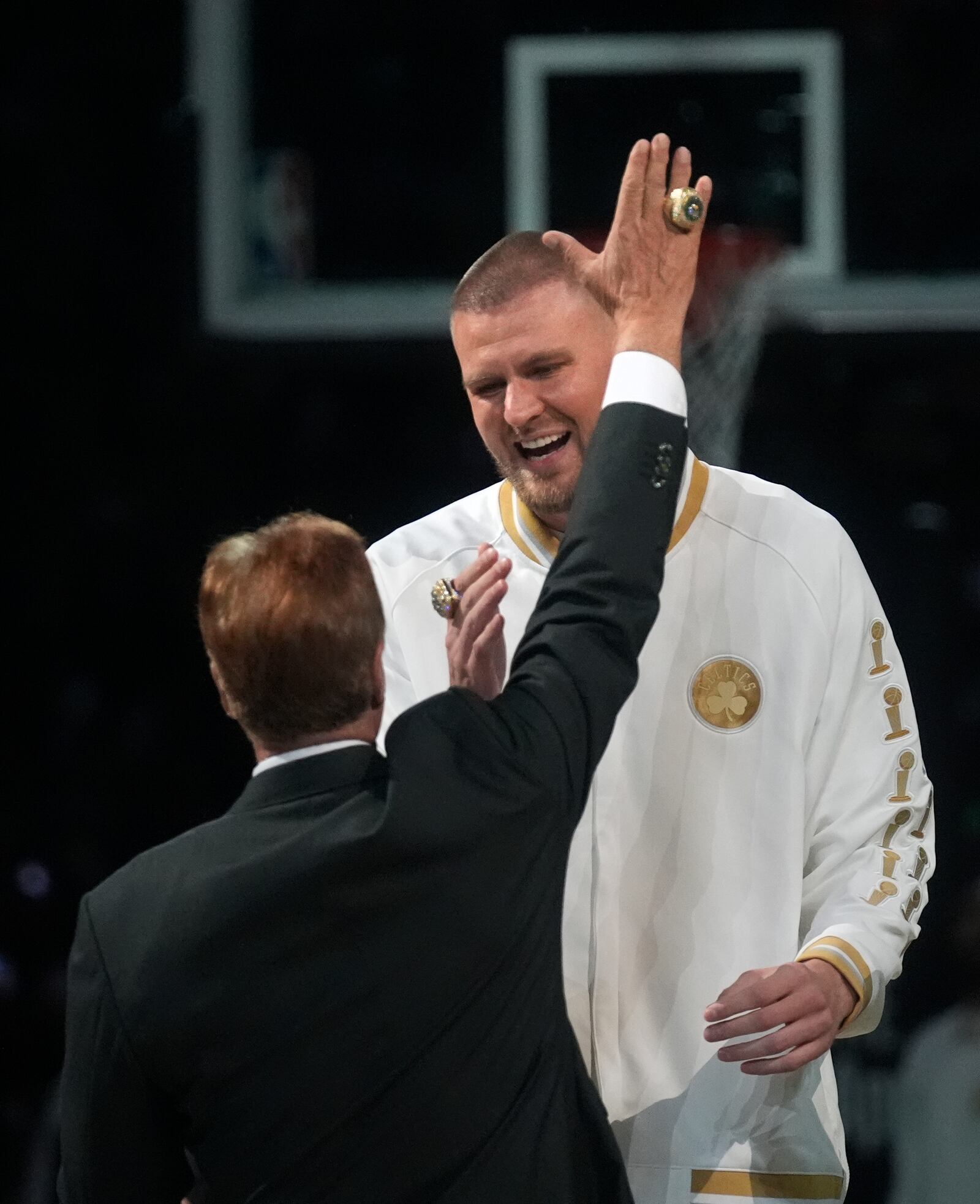 Boston Celtics center Kristaps Porzingis, celebrates with team owner Steve Pagliuca during a ceremony where the 2024 NBA Championship banner was raised prior to an NBA basketball game against the New York Knicks, Tuesday, Oct. 22, 2024, in Boston. (AP Photo/Charles Krupa)