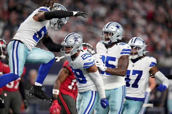 Dallas Cowboys' Buddy Johnson, left, and Andrew Booth Jr. (25) celebrate with C.J. Goodwin (29) after Goodwin made a stop on a punt coverage in the second half of an NFL football game against the Tampa Bay Buccaneers in Arlington, Texas, Sunday, Dec. 22, 2024. (AP Photo/Julio Cortez)