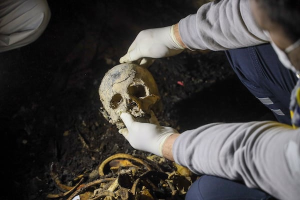 A Syrian civil defense worker, known as a White Helmet, holds a skull while inspecting human remains found in two separate basements in Sbeneh, outskirts of Damascus, Syria, Tuesday, Jan. 28, 2025. According to the White Helmets, the charred remains belong to at least 26 victims of the Bashar Assad regime. (AP Photo/Omar Albam)