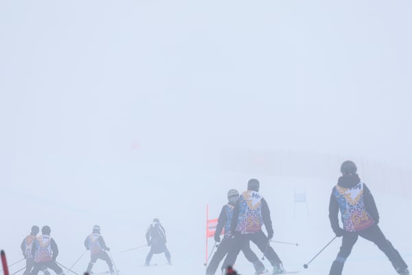 Race officials descend the course after an alpine ski, women's World Cup Super G race was canceled due to strong winds and poor visibility, in St. Moritz, Switzerland, Sunday, Dec. 22, 2024. (AP Photo/Marco Trovati)