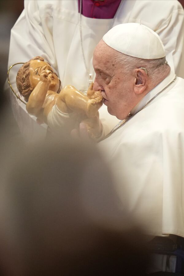 Pope Francis kisses a wooden statuette of the infant Jesus at the end of a mass in St. Peter's Basilica at The Vatican on New Year's Day, Wednesday, Jan. 1, 2025. (AP Photo/Andrew Medichini)