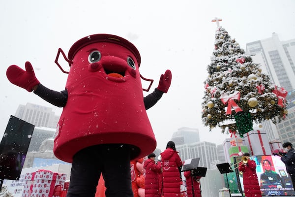 A volunteer man wearing a costume of a Salvation Army pot stands near a snow-covered Christmas tree in Seoul, South Korea, Wednesday, Nov. 27, 2024. (AP Photo/Ahn Young-joon)