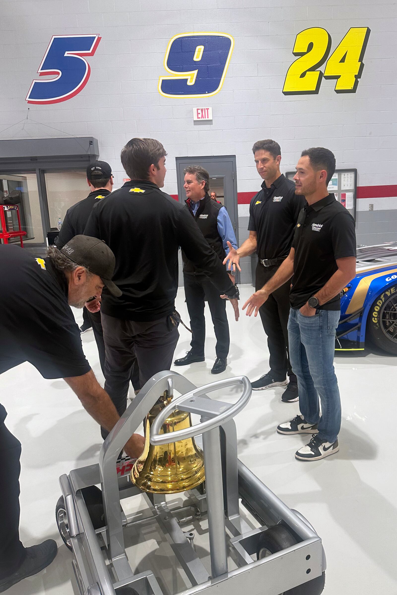 Hendrick Motorsports vice chairman Jeff Gordon, center rear, crew chief Cliff Daniels, second from right, and NASCAR driver Kyle Larson shake hands with Hendrick Motorsports teammates during the victory bell ringing ceremony for Larson’s win at Bristol Motor Speedway, Oct. 9, 2024, at Hendrick Motorsports in Charlotte, N.C. (AP Photo/Jenna Fryer)