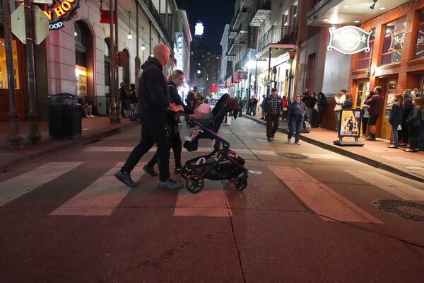 A couple pushes a child in a stroller on Bourbon Street at the site of a deadly truck attack on New Year's Day in New Orleans, Friday, Jan. 3, 2025. (AP Photo/Gerald Herbert)