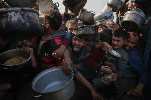 Palestinians struggle to reach for food at a distribution center in Khan Younis, Gaza Strip, Friday, Jan. 9, 2025. (AP Photo/Abdel Kareem Hana)